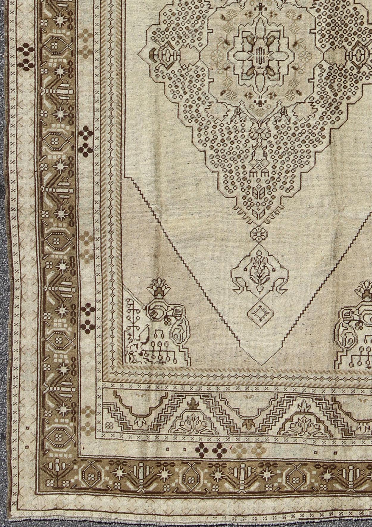 Vintage Turkish Stylized Medallion Oushak Rug in Sandy Neutrals and Earth Tones Measures: 5'7 x 10'2 This vintage Turkish Oushak sets on a neutral sandy ground with a central medallion stylized with small details. The background is ... - Keivan Woven ArtsTU - UGU - 56 - 2854Rug