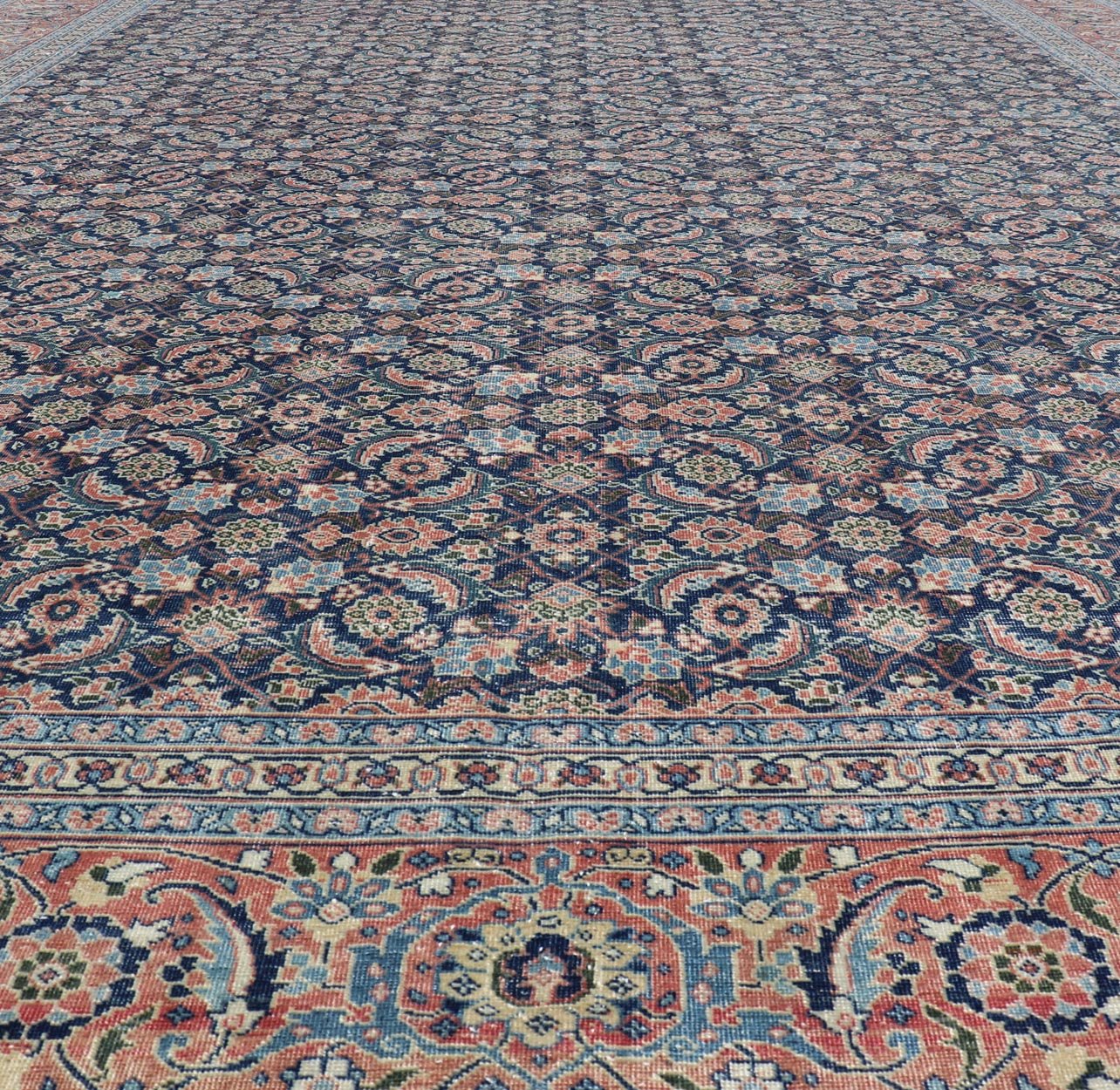 Antique Hand - Knotted Persian Tabriz with Sub - Geometric Floral Design in Wool This antique Persian Tabriz rug features an all - over, sub - geometric floral design rendered in green, coral, orange, ivory and blue shades, set upon a navy blue backgro... - Keivan Woven ArtsV21 - 1206 - 18431
